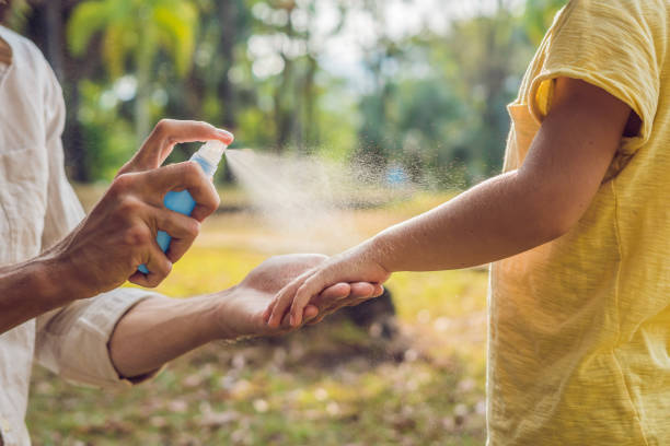 dad and son use mosquito spray.Spraying insect repellent on skin outdoor.